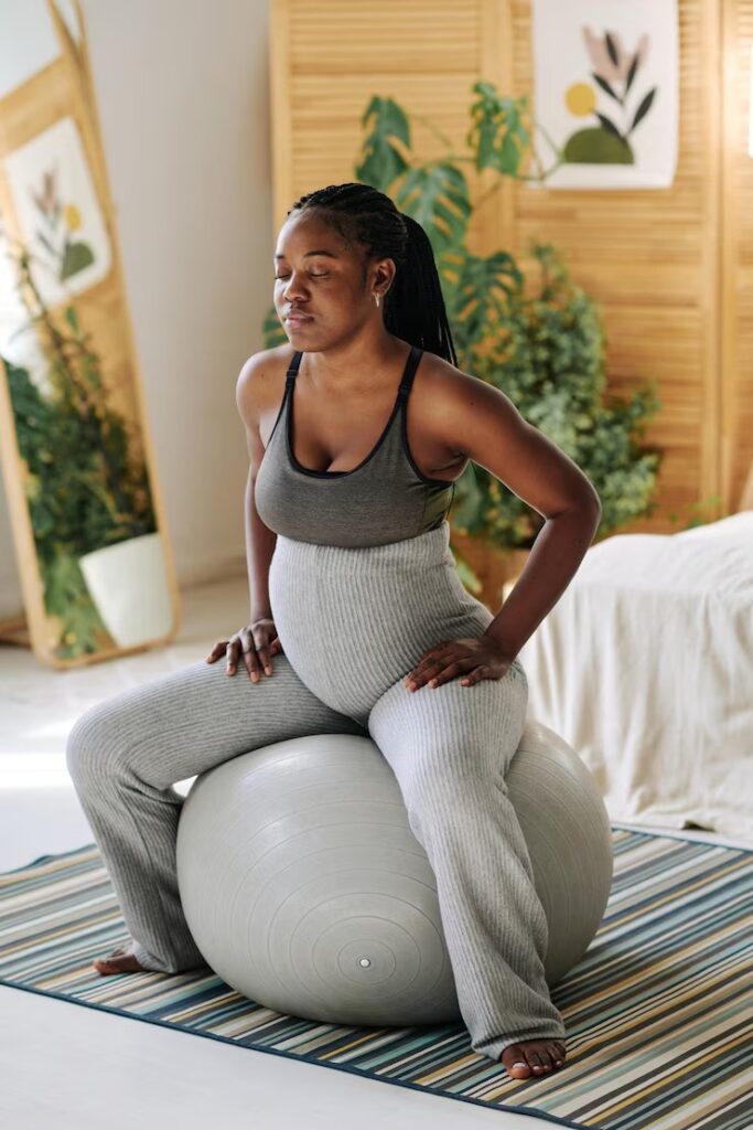 Pregnant girl sitting on a fitness ball concentrating with her eyes closed